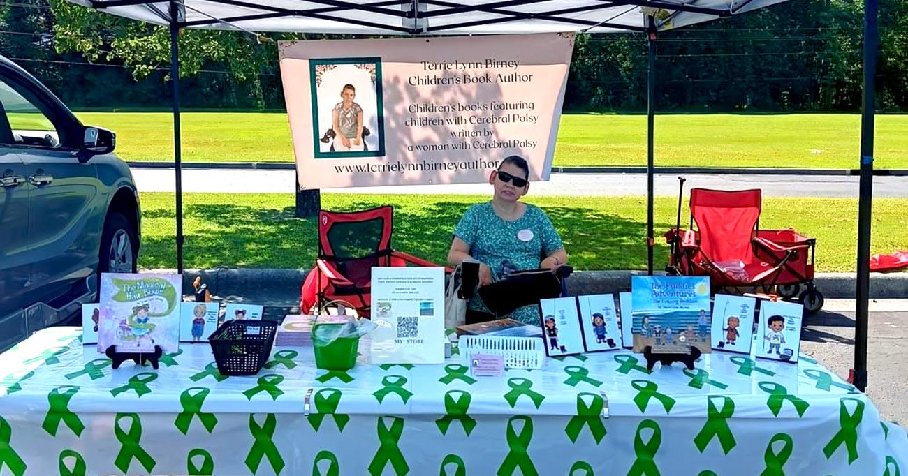 Terrie Lynn Birney behind a display of children's books at an outdoor fair