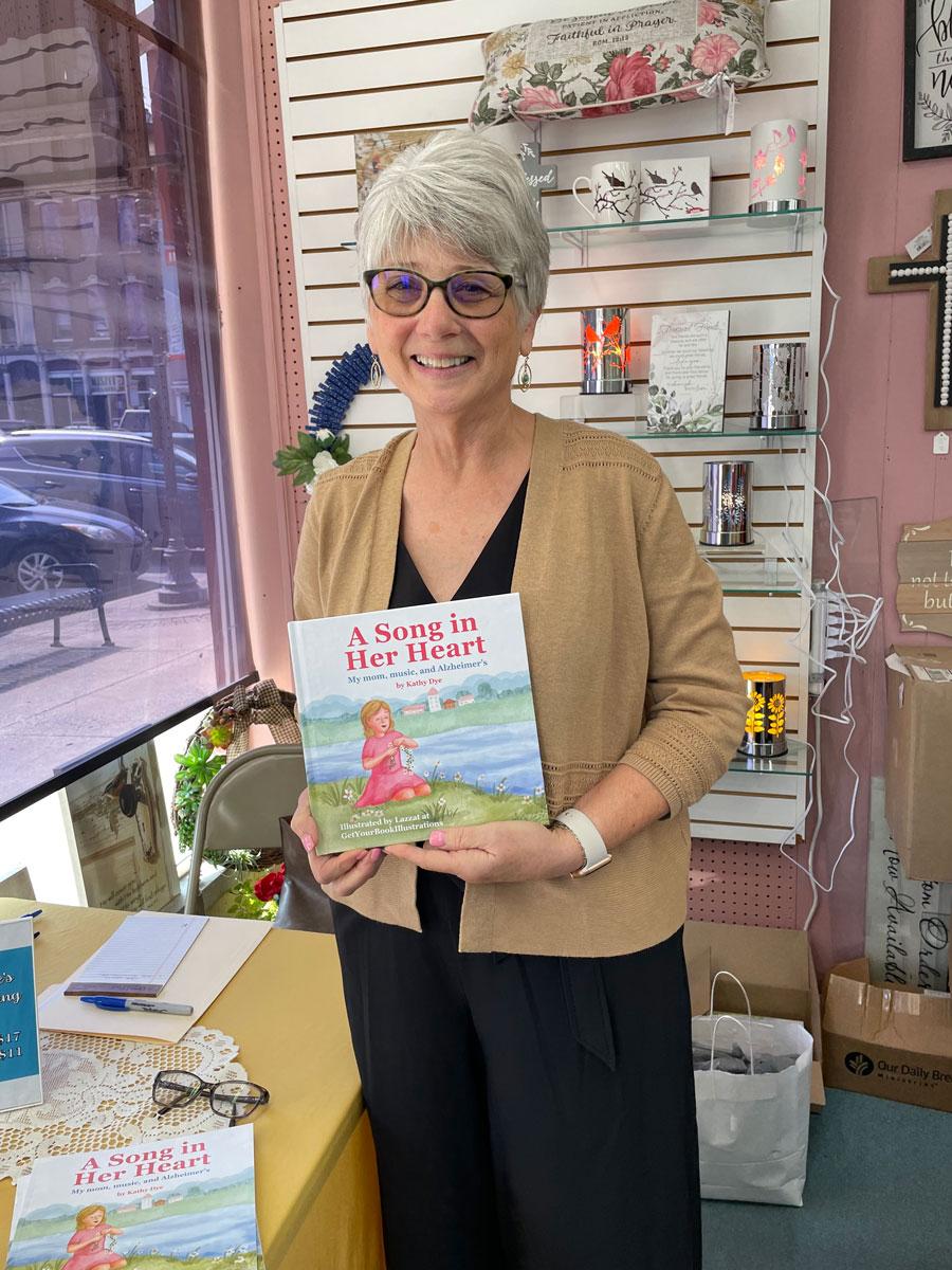 Kathy Dye holding A Song in Her Heart inside a bookstore
