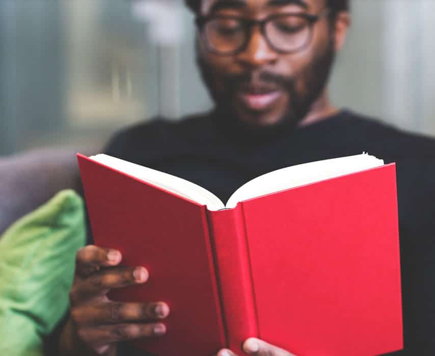 A man is reading a book and smiling.
